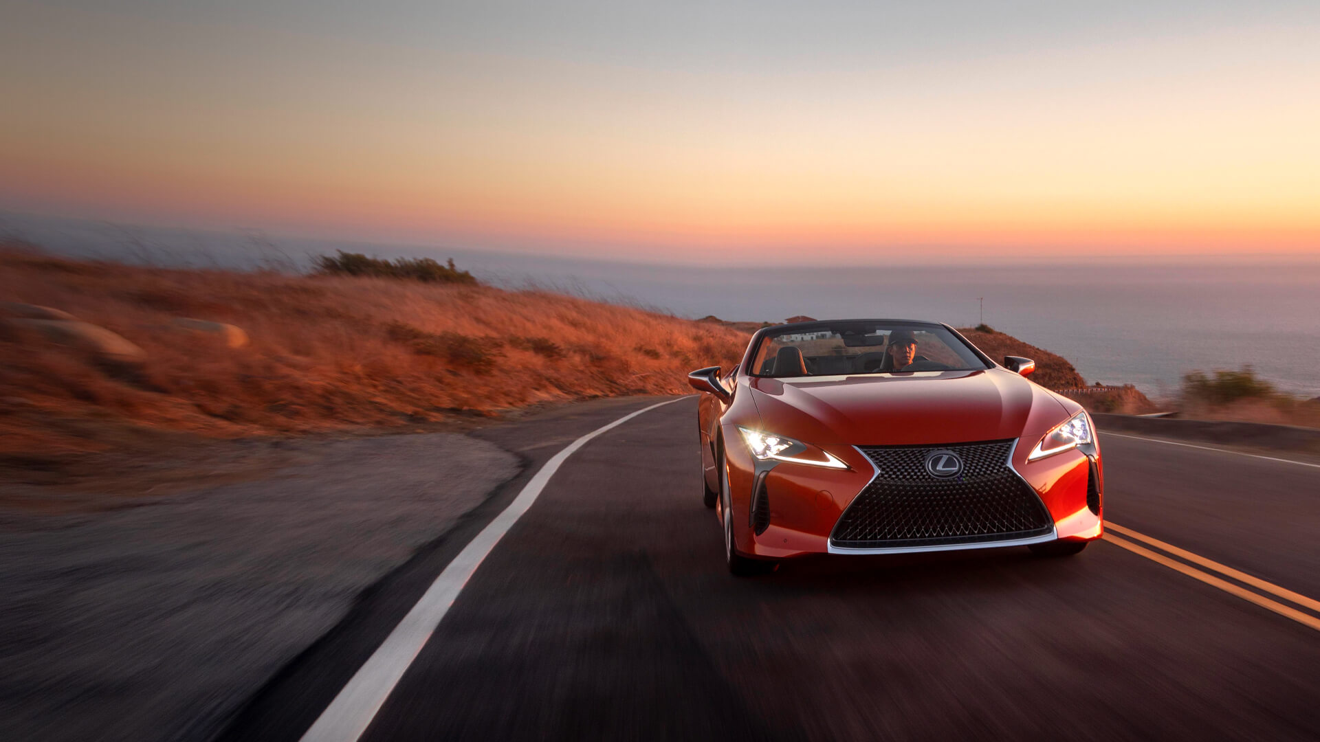 Red Lexus LC Convertible being driven on the road with the top down.
