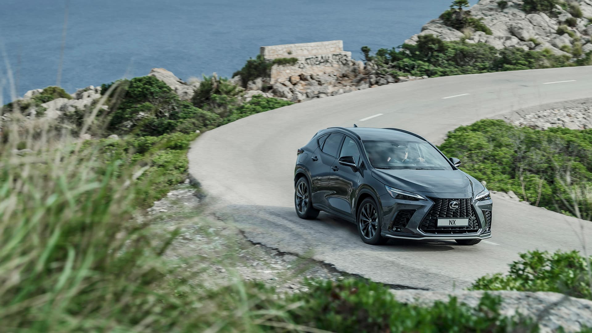 Grey NX being driven on a winding road.