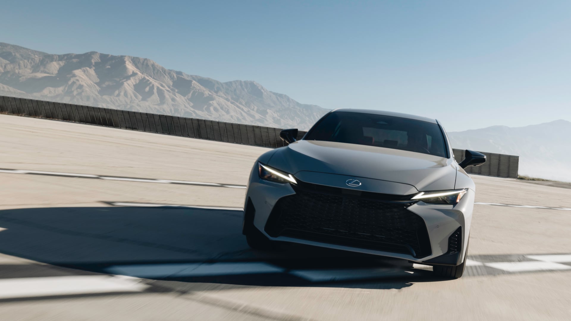 White Lexus IS being driven on the road.